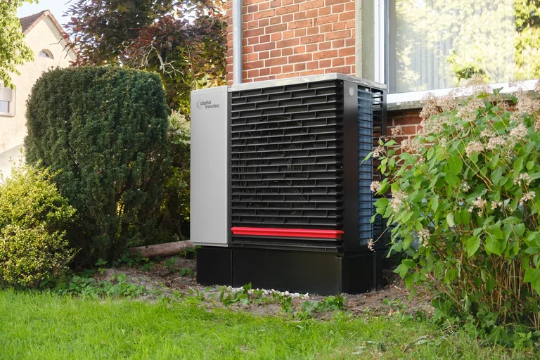 An outdoor heat-pump unit beside a brick home