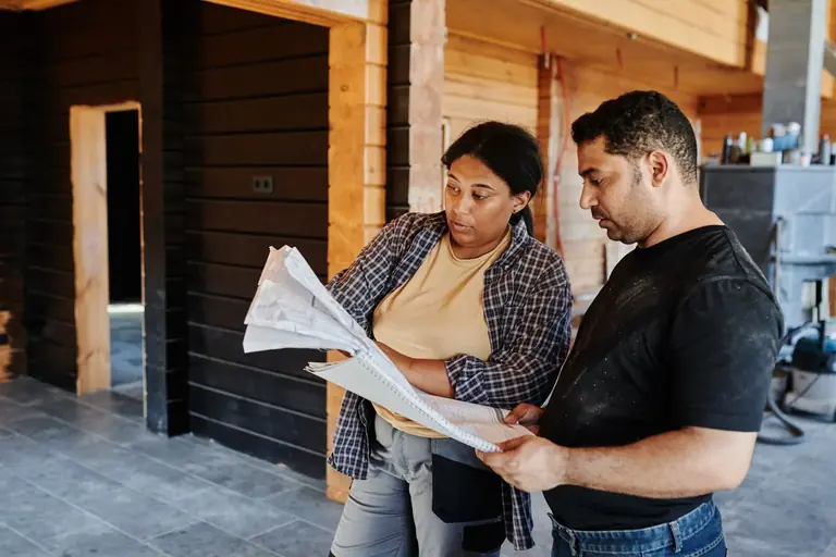 Two people discussing project scope inside a home under renovation