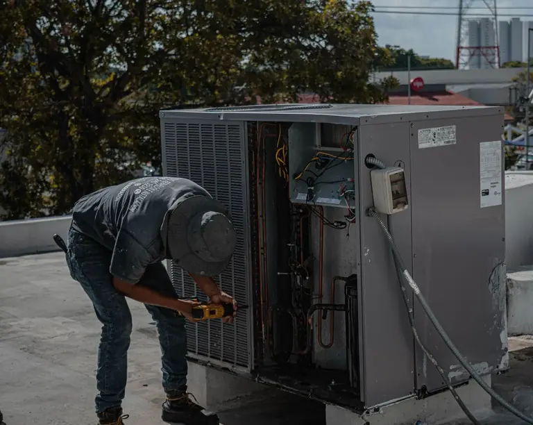 Technician working on outdoor heating and cooling equipment