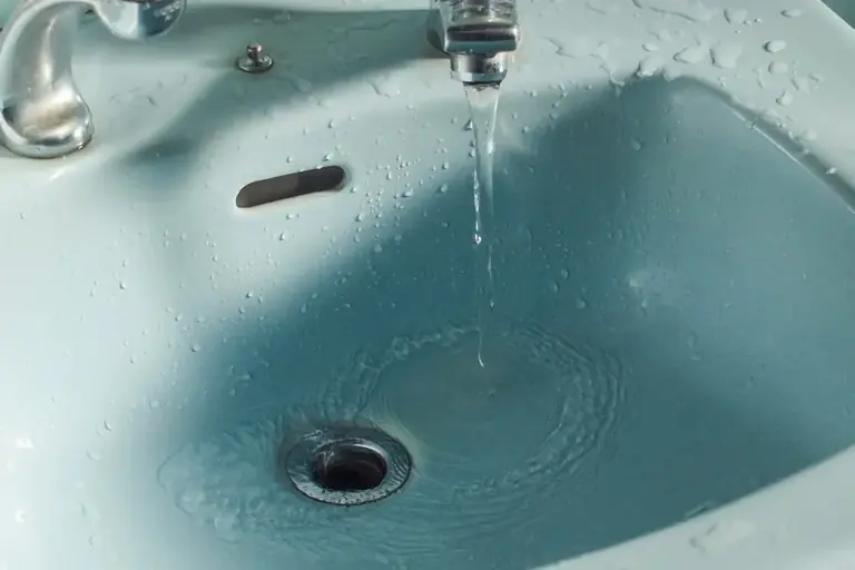 A dripping faucet above a blue sink