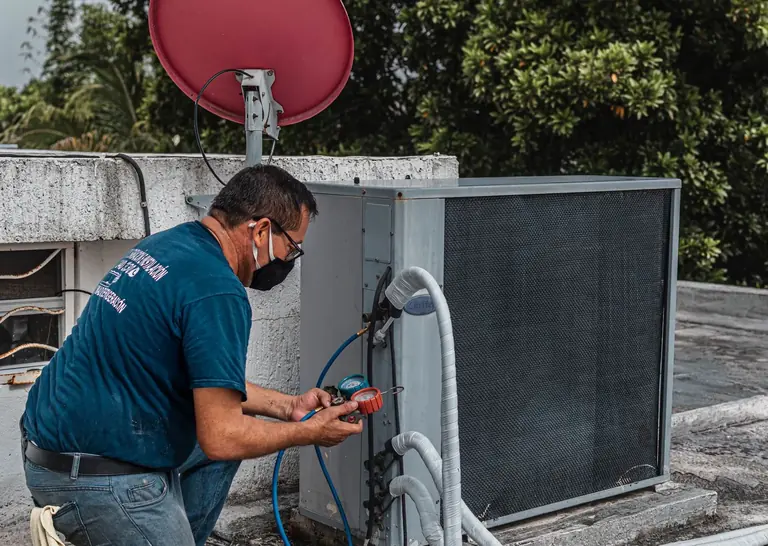 Technician inspecting outdoor heating and cooling equipment