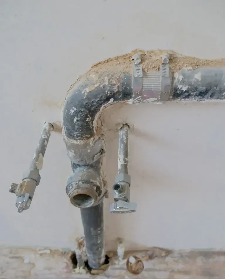Exposed plumbing connections and shutoff valves at an opened wall