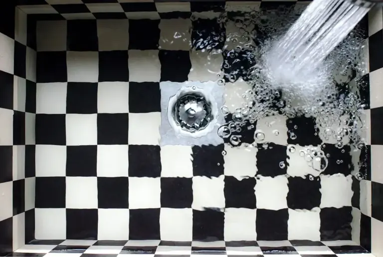 Water running into a tiled basin around a visible drain
