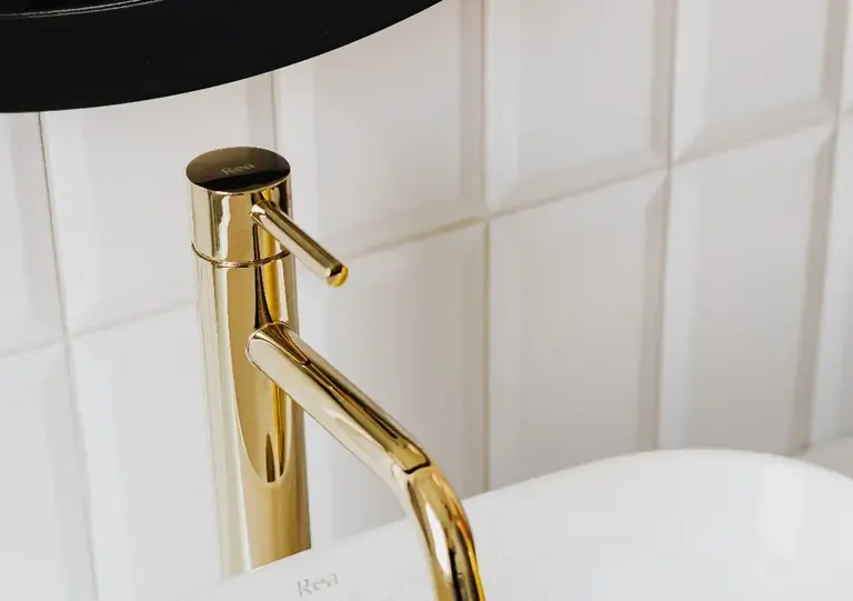 A tall brass single-hole faucet beside a vessel basin